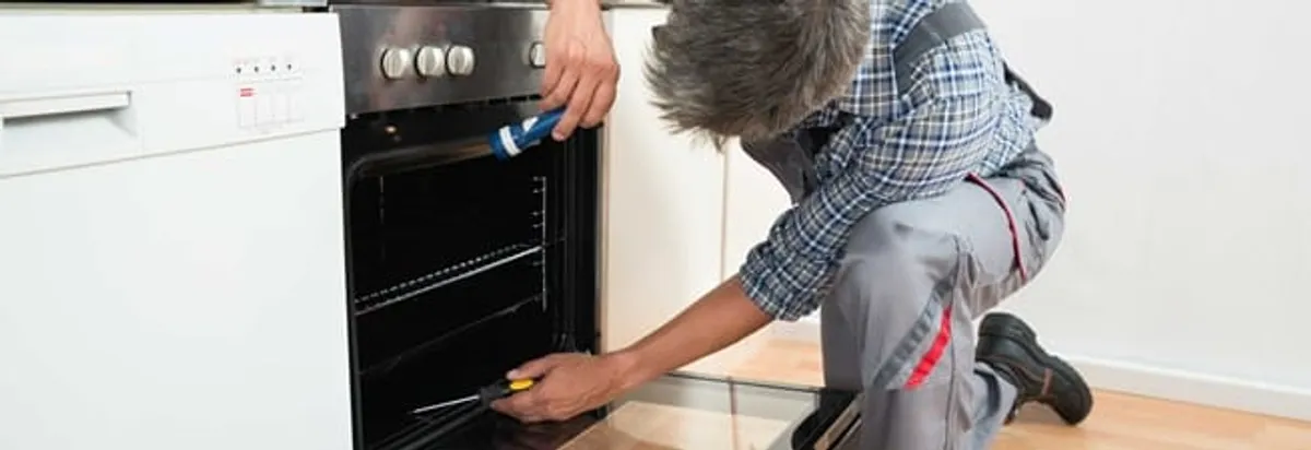 Oven repair technician inspecting and servicing an electric oven in Hollywood, FL