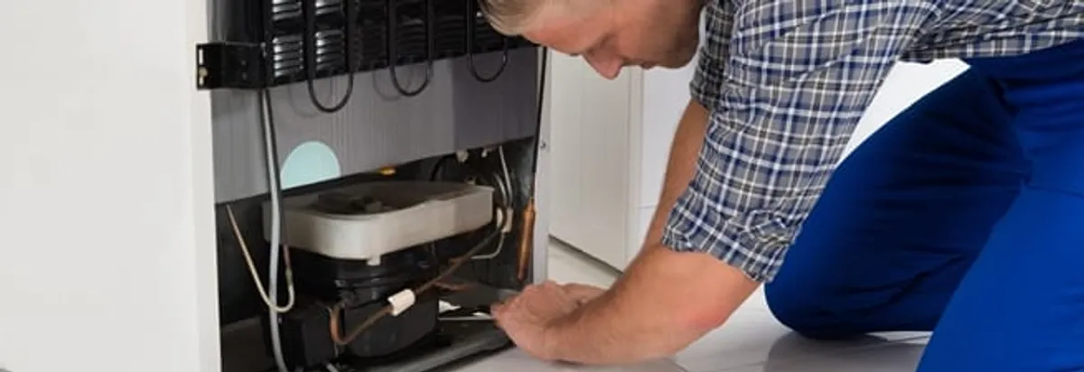 Refrigerator repair technician servicing the compressor and condenser area in Hollywood, FL